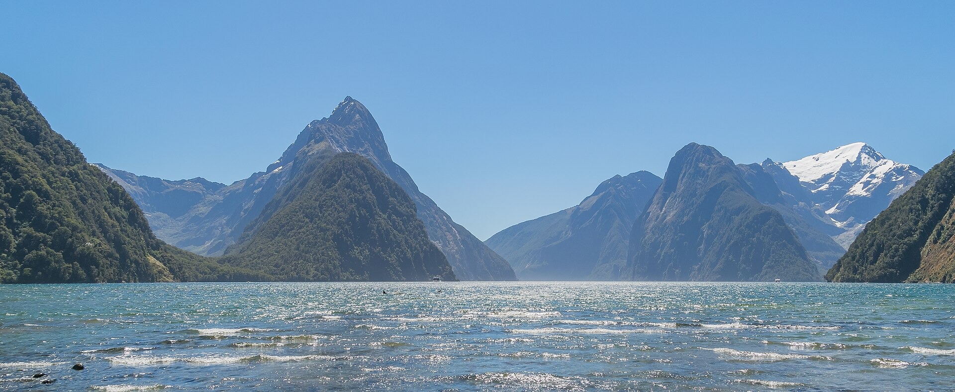 Mitre Peak and the mountains of Milford Sound rising above the water under a blue sky