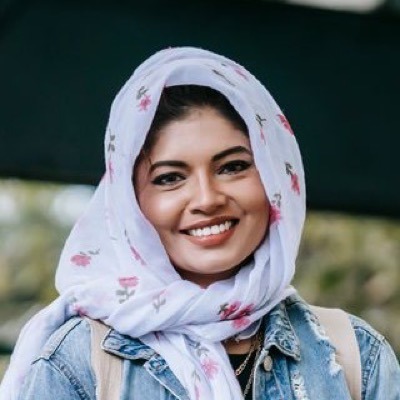 Alisha Rahman, a smiling student in a floral headscarf and denim jacket