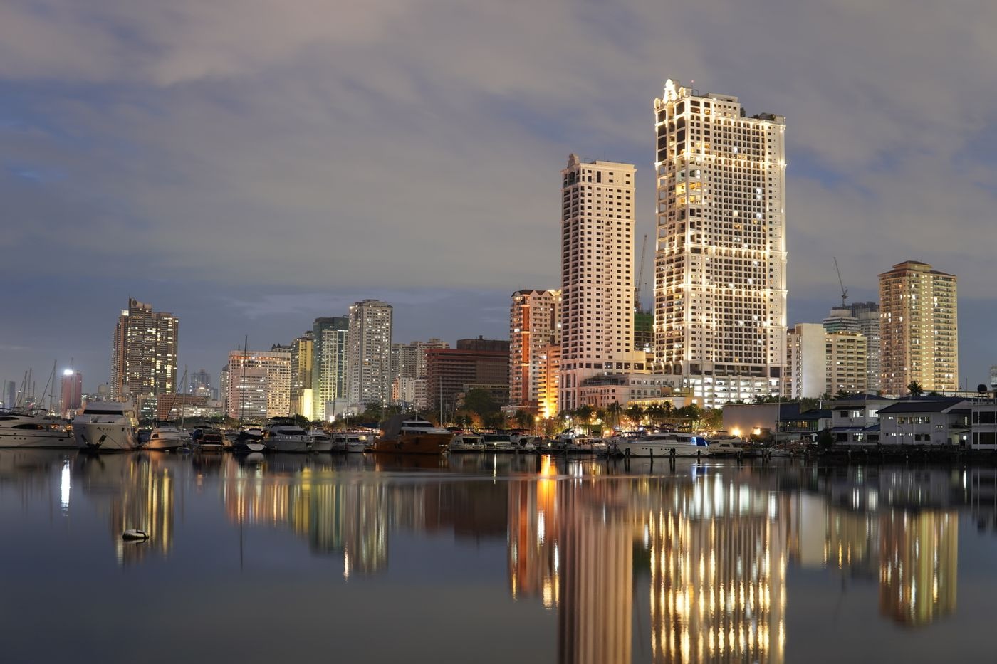 Manila skyline lit up at twilight, reflected in the bay